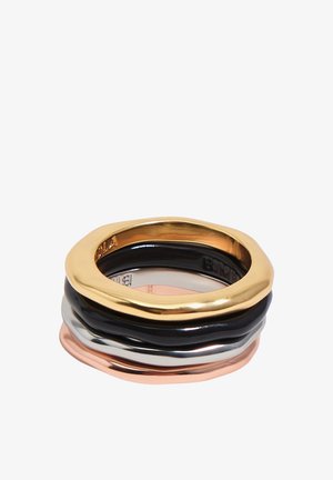 Stacked rings in polished gold, black, silver, and rose gold with irregular, organic shapes on a white background.