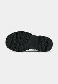 Suela de zapato de goma negra con surcos profundos, logo de la marca grabado y recortes en forma de corazón para proporcionar tracción y un detalle de diseño.