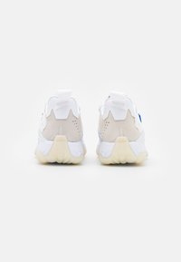 Sneakers med vit och ljusgrå färgsättning, i mocka och mesh-material, unik bakre design och gummisulor med texturerade detaljer.