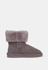 Stivaletto in suede grigio con una morbida mansciorra di pelliccia grigia, punta arrotondata e dettagli di cucitura discreti. Suola in gomma piatta per stabilità.