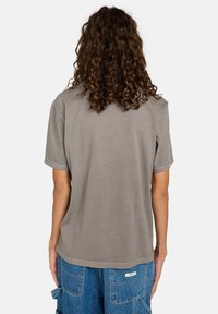 Luźna szara koszulka bawełniana z krótkimi rękawami i zaokrąglonym dołem, bez wzorów z tyłu, zestawiona z niebieskimi szortami cargo.