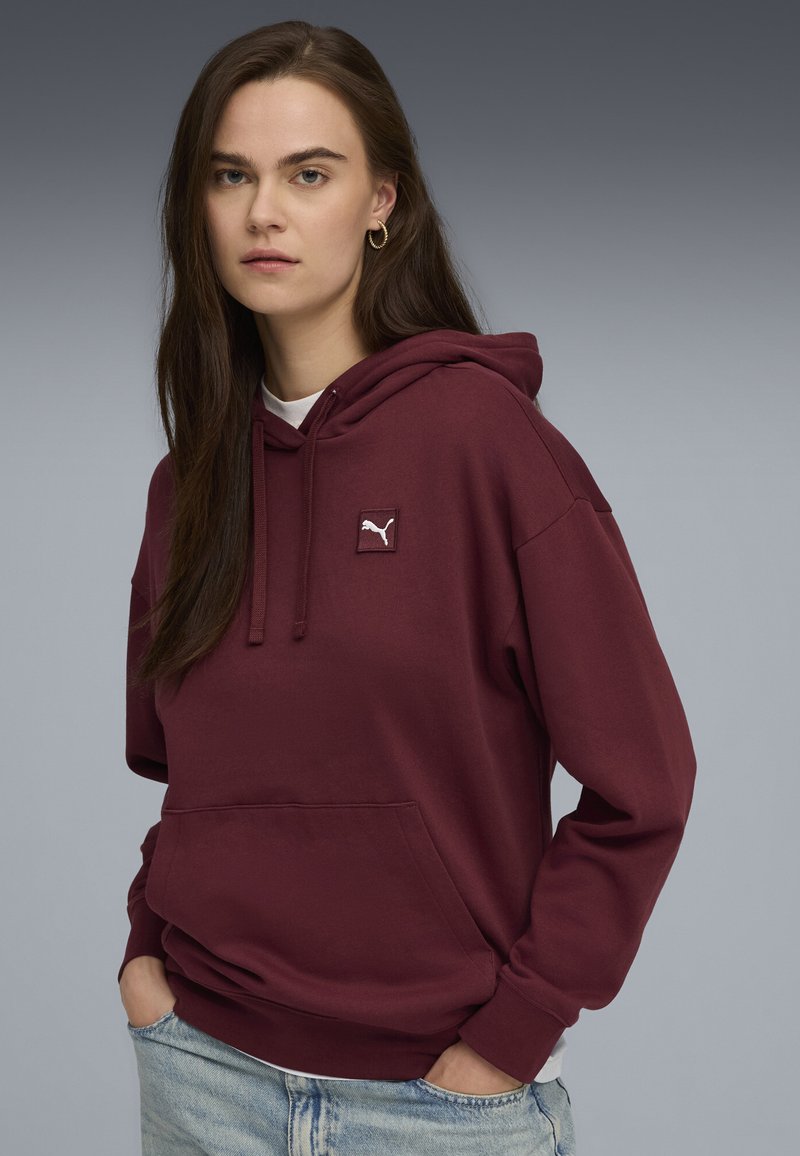 Bordeaux värvi kapuutsiga pusa, millel on nöör ja eesmine tasku, ning rinnal väike valge Puma logo. Pehme ja mugav lõige.