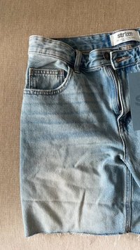 Svjetloplave traper šortse s istrošenim rubovima, klasičnim pet džepovima i zatvaračem. Oznaka glasi "str teen" s veličinom 38.