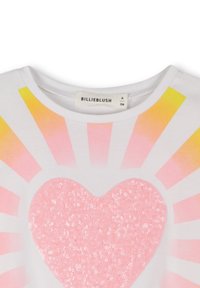 Witte t-shirt met een groot rozengekleurd pailletten hartontwerp, omringd door gestileerde stralen in roze en geel, gelabeld "BILLIEBLUSH."