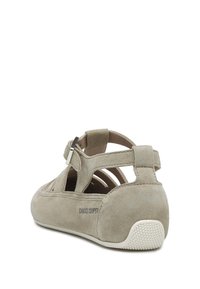 Chaussure en suède beige avec un design découpé et une sangle ajustable, dotée d'une semelle en caoutchouc texturé et d'un talon renforcé pour le soutien.