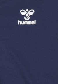 Mørkeblå t-shirt lavet af blødt stof med en glat tekstur; har et hvidt Hummel-logo og et minimalistisk design.