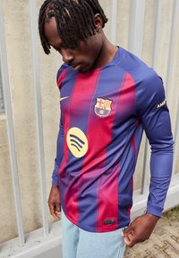 Barça majica s dugim rukavima u plavim i bordo prugama, Nike logo, Spotify grafika i FCB grb. Detaljno šivenje i atletski kroj.