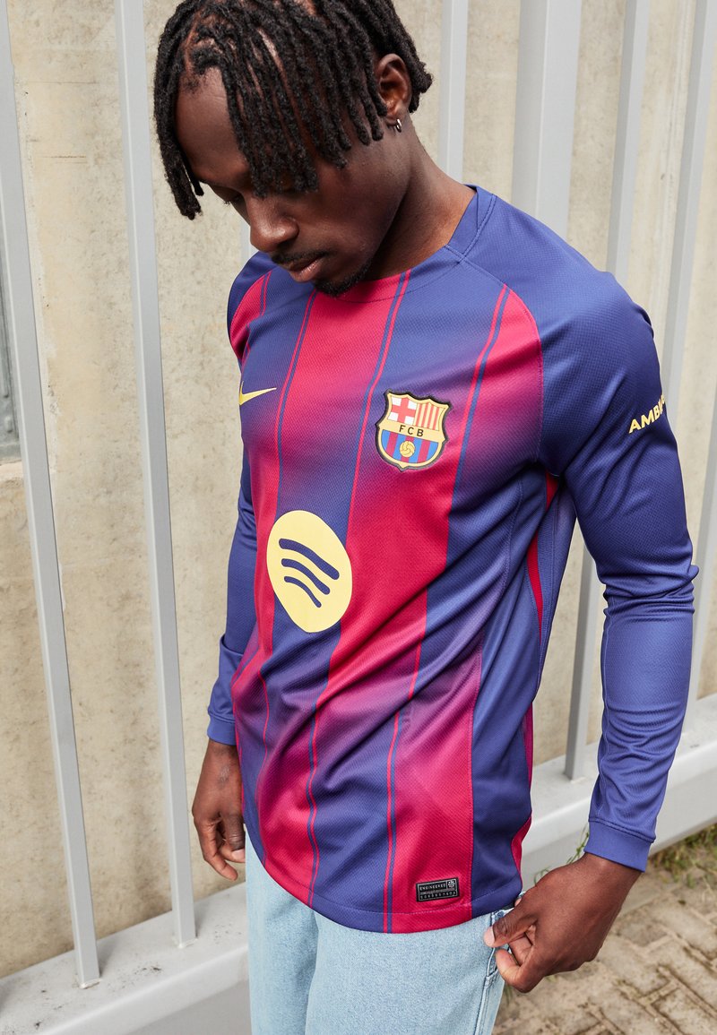 Barça majica s dugim rukavima u plavim i bordo prugama, Nike logo, Spotify grafika i FCB grb. Detaljno šivenje i atletski kroj.