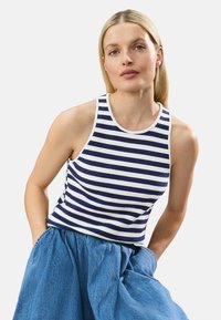 Marineblå og hvidstribet tanktop med ribbet tekstur, rund halsudskæring og ærmeløs design. Sammen med en lyseblå, tekstureret nederdel.