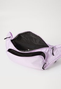 Borsa a tracolla viola realizzata in materiale morbido con molteplici scomparti con zip, con una fodera interna nera e spallacci regolabili.