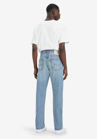 Lichtblauwe high-waisted jeans met een rechte pasvorm, voorzien van achterzakken en een label op de tailleband. Gecombineerd met een wit T-shirt.