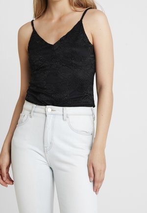 Zwarte kanten cami met een V-hals en dunne bandjes, gecombineerd met lichtgekleurde hooggetailleerde spijkerbroeken met een klassiek ontwerp met vijf zakken.