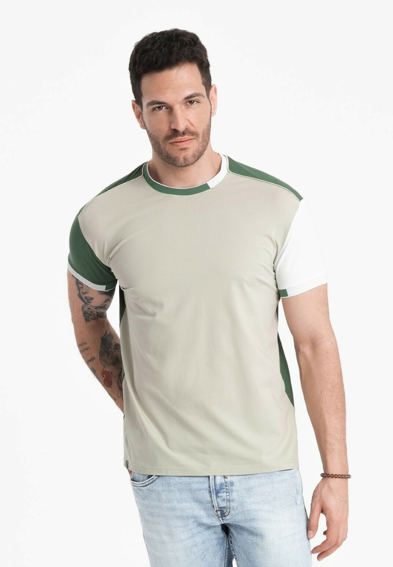 Kratký rukáv tričko v béžové barvě s zelenými a bílými akcenty, s kulatým výstřihem a slim fit. Materiál se zdá být hladký.