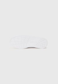 Suola di sneaker bianca con un motivo di grip testurizzato, caratterizzata da una superficie liscia e un branding minimale. Punta arrotondata e design leggero.