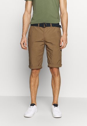 Shorts marroni con orli arrotolati, realizzati in tessuto leggero. Abbinati a una camicia verde e sneakers bianche, con una cintura blu navy.