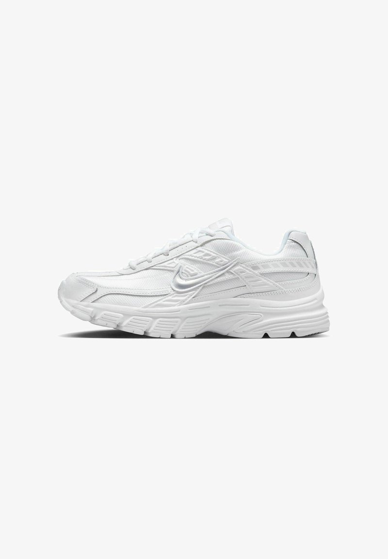 Baskets d’athlétisme blanches avec semelle texturée, tige en mesh et synthétique, et logo Nike swoosh argenté sur le côté.