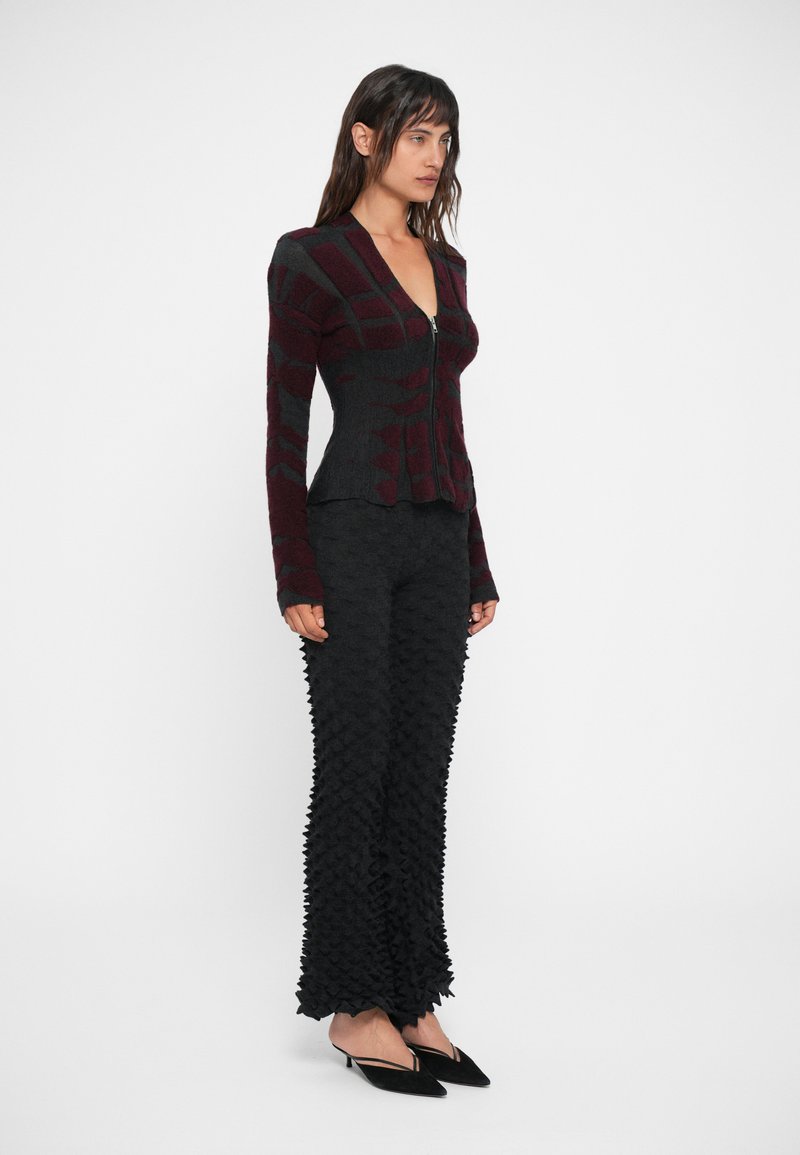 Gilet ajusté à motifs bordeaux et gris avec fermeture éclair à l'avant, associé à un pantalon noir évasé texturé présentant un design en pic 3D.