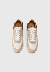 Sneakers i nyanser av beige, hvit og brun; laget av semsket skinn og mesh; har flate hvite snører og et rundt tådesign.