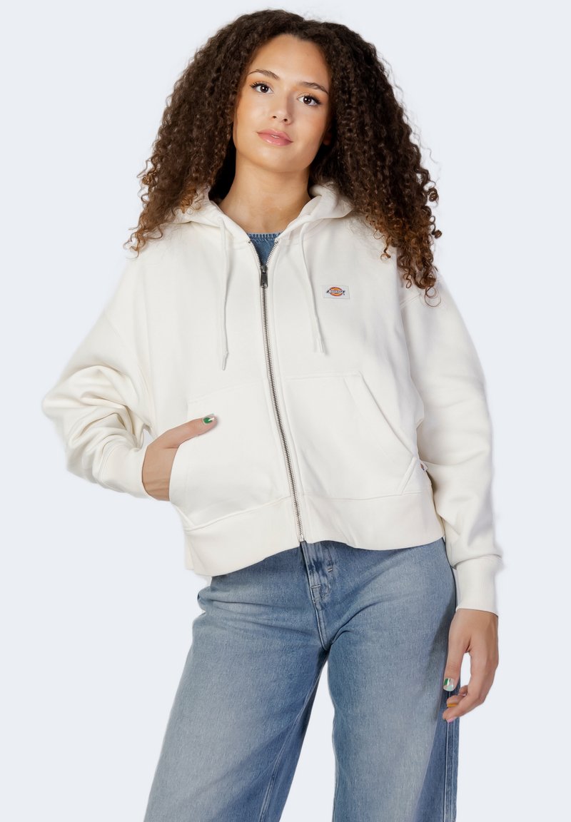 Felpa bianca con zip realizzata in morbido cotone, dotata di cappuccio con cordino, tasche davanti e un piccolo logo sul lato sinistro del petto.