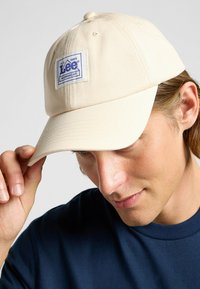 Beige basebollkeps i bomull med en strukturerad krona, en mjuk skärm och en Lee Workwear-logotyp på framsidan.