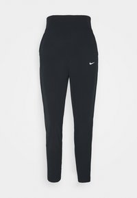 Zwarte sportbroek met een hoge tailleband, taps toelopende benen en een klein wit Nike-logo aan de voorkant. Gemaakt van rekbare, soepele stof.