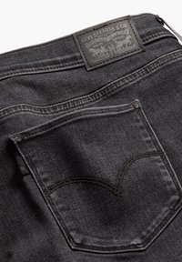 Donkerdenim jeans met een zwart leren label van Levi Strauss & Co., een achterzak met kenmerkende stitching, en een soepele textuur.