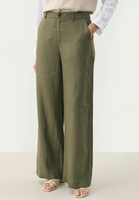 Pantaloni a gamba larga verde oliva realizzati in un materiale leggero e testurizzato, con chiusura a bottone e tasche laterali. Vestibilità casual e ampia.