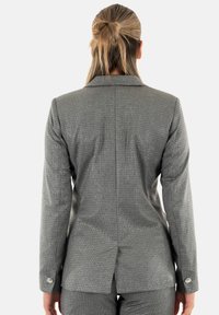 Blazer grigio con texture, dalla vestibilità su misura, con rever a taglio e dettagli con bottoni sulle maniche, dotato di uno spacco singolo sul retro.