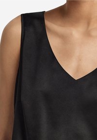 Haut sans manches noir avec un décolleté en V profond, fabriqué en tissu lisse, avec une coupe décontractée et un design minimaliste.