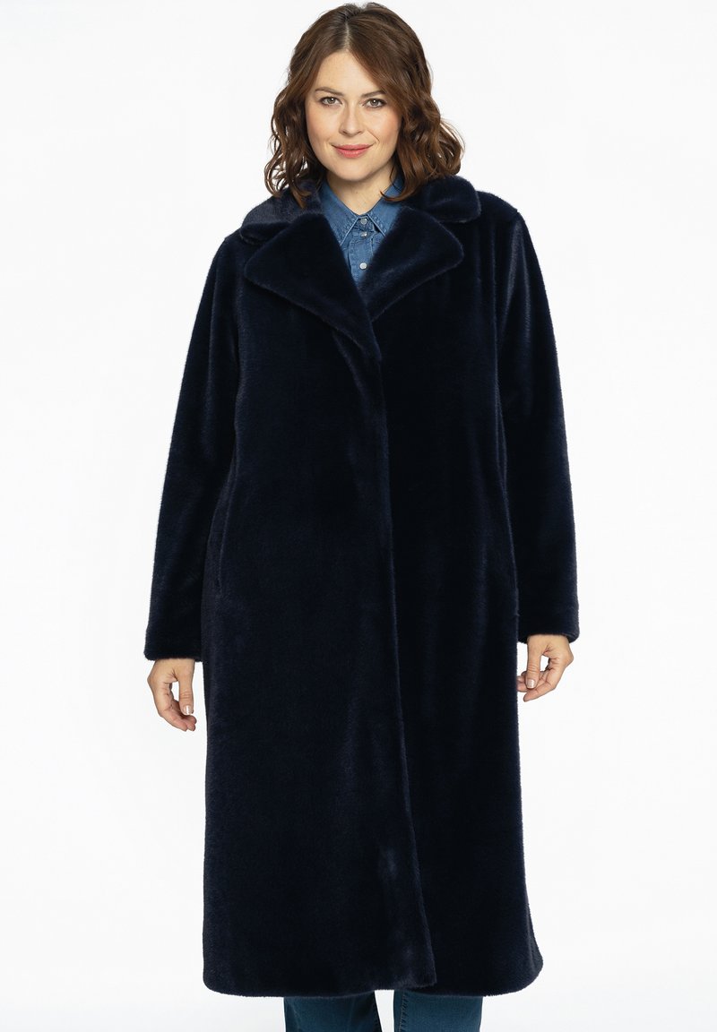 Lakeret frakke i navyblåt imiteret pels med bred krave, lange ærmer og sidelommer, der har en blød tekstur og knælængde design.