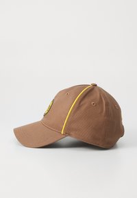 Brown baseball cap with yellow accents and a circular logo on the front, featuring a curved brim and six-panel design.