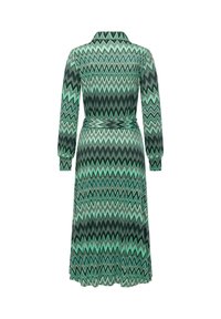 Langärmeliges Kleid mit einem grünen und schwarzen Zickzackmuster, tailliert, mit Kragen, fließender Silhouette und weicher Textur.