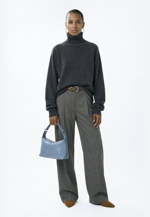 Woman wearing dark gray turtleneck sweater, gray wide-leg pants with leopard print belt, brown shoes, holding blue handbag with textured pattern.
