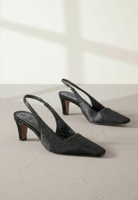 Čierne slingback topánky s špicatou špičkou, vyrobené z textúrovaného materiálu, s nízkym dreveným opätkom a nazúvacími dizajnom.