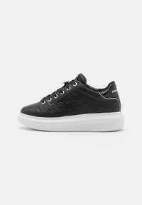 Sneaker in pelle nera con motivo logo inciso, suola in gomma bianca, punta tonda e dettagli in occhioletto argentato. Texture liscia, design a collo basso.