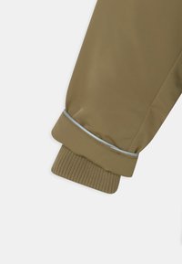 Khaki jacket sleeve with knit cuff and a reflective strip near the wrist on a plain white background.