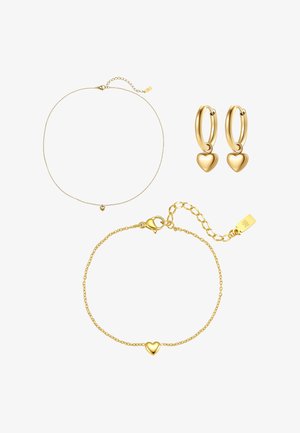 Conjunto de joyas de oro con un delicado collar de cadena, pulsera con colgante de corazón y pendientes de aro con colgantes en forma de corazón sobre un fondo blanco.