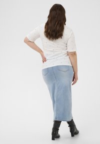 Biała koszulka z krótkim rękawem, z małymi niebieskimi wzorami w kształcie serc. Jasnoniebieska spódnica dżinsowa z tylnymi kieszeniami, czarne botki za kostkę.