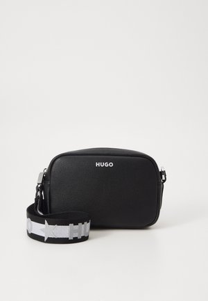 Sort læder crossbody taske med sølv "HUGO" logo og justerbar sort- og hvid rem med stjerne- og tekstdetaljer.
