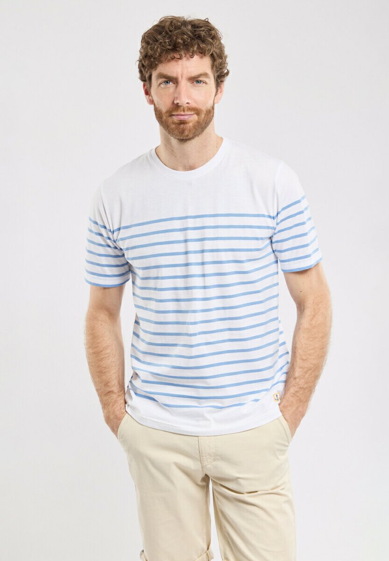 T-shirt blanc en coton avec des rayures horizontales bleu clair, col rond, manches courtes et une petite étiquette logo près de l'ourlet.