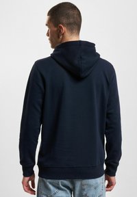 Dunkelblauer Pullover-Hoodie mit einer Kordelzugkapuze, aus weichem Stoff gefertigt, mit gerippten Bündchen und Saum, sichtbarem Nahtdetail.