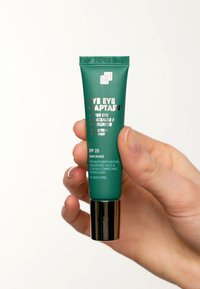 Tubo verde di correttore e idratante per il contorno occhi "Eye Eye Captain" con accenti argentati. Mostra SPF 25, tonalità chiara e dettagli sugli ingredienti principali.