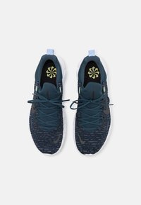 Niebieskie i zielone sportowe buty w wzory, wykonane z siatki, z białą podeszwą i kontrastującymi akcentami, w tym sznurówkami i detalami logo.