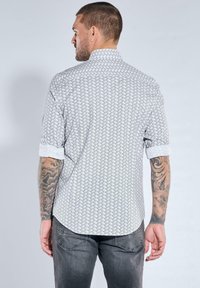 Hellgraues Kurzarmhemd mit einem gewebten Muster, ausgestattet mit einem klassischen Kragen und hochgekrempelten Ärmeln, von hinten gezeigt.