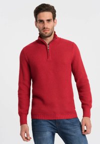 Rode gebreide trui met een gestructureerd patroon, halve rits-kraag en geribde manchetten en zoom. Gemaakt in combinatie met blauwe jeans, is het ontwerp casual en aansluitend.
