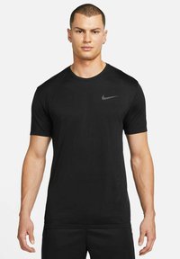 T-shirt desportivo preto feito de tecido leve. Apresenta mangas curtas e gola redonda. Design texturizado nos ombros. Logótipo da Nike em cinza.