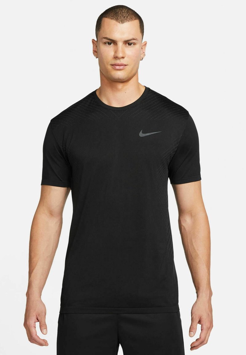 T-shirt desportivo preto feito de tecido leve. Apresenta mangas curtas e gola redonda. Design texturizado nos ombros. Logótipo da Nike em cinza.