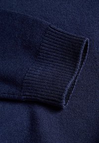 Maglione lavorato a maglia blu navy con dettagli a coste sui polsini. Texture morbida con una finitura liscia, corpo senza cuciture e design minimalista.