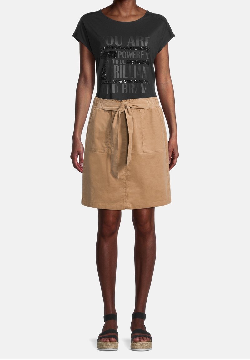Svart t-shirt med paljetter och inspirerande text, kombinerad med en beige A-linje-formad kjol med knytmidja och framfickor.