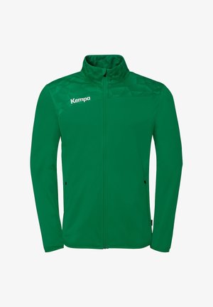 Green full-zip jacket with stand collar, subtle geometric pattern on shoulders, and white "Kempa" logo on the left chest.